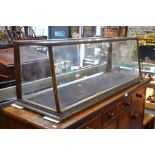 An antique glazed panel shop counter display cabinet with raked front,