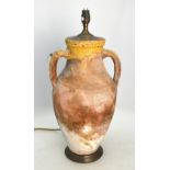 A classical terracotta amphora with incised wheel decoration, two strap handles converted to a lamp,
