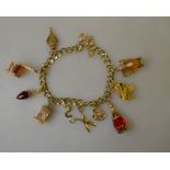 A yellow metal curb charm bracelet with bolt ring snap having ten various charms attached,