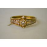 A Victorian bloomed unmarked gold diamond set bangle, the central old cut diamond approx 0.