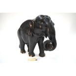 A large ebony elephant holding a tiger in its trunk,