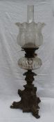 A Victorian oil lamp with an etched glass shade, faceted glass reservoir and a leaf scrolling bronze