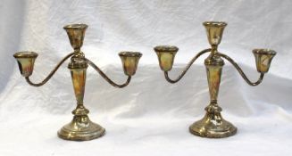 A pair of white metal two branch candelabra with scrolling arms ,