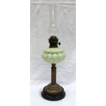 A Victorian oil lamp with a moulded opaque green glass reservoir on a reeded brass column,