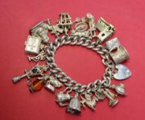 A silver charm bracelet, set with numerous charms including a candlestick telephone, lamp,