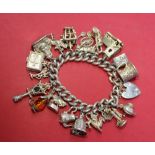 A silver charm bracelet, set with numerous charms including a candlestick telephone, lamp,