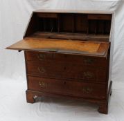 An 18th century oak bureau the sloping fall enclosing pigeon holes and drawers above four long