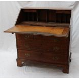 An 18th century oak bureau the sloping fall enclosing pigeon holes and drawers above four long