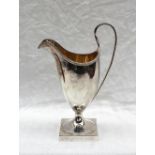 A George III silver helmet shaped cream jug, with a beaded rim, and gilt interior, on a square foot,