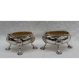 A pair of George III silver open table salts of oval form with a gadrooned edge on four shell