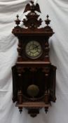 A walnut Vienna regulator type wall clock with an eagle surmount, half section columns,