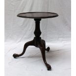 A 19th century mahogany tripod table with a dished top and moulded rim on a turned baluster column