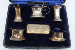 A George V silver cruet including a pair of pepperettes, a pair of salts and a mustard pot,