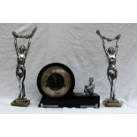 An Art Deco clock garniture, comprising an ebonised mantle clock with chrome seated figure,