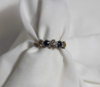 A diamond and sapphire five stone ring set with three old brilliant cut diamonds to a white metal