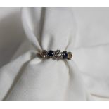 A diamond and sapphire five stone ring set with three old brilliant cut diamonds to a white metal