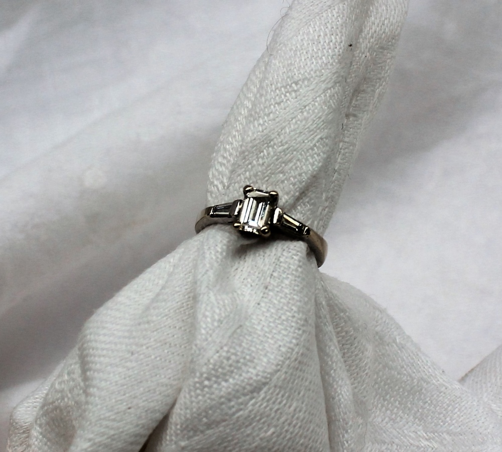 A solitaire diamond ring, the emerald cut diamond measuring 5mm x 4mm x 2mm,