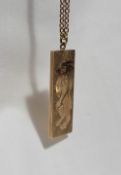A 9ct yellow gold ingot, decorated with a lion, on a yellow metal chain marked 9ct,
