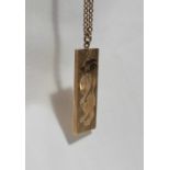 A 9ct yellow gold ingot, decorated with a lion, on a yellow metal chain marked 9ct,