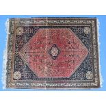 A rug with a central diamond panel with a red ground decorated with stylised flower heads with