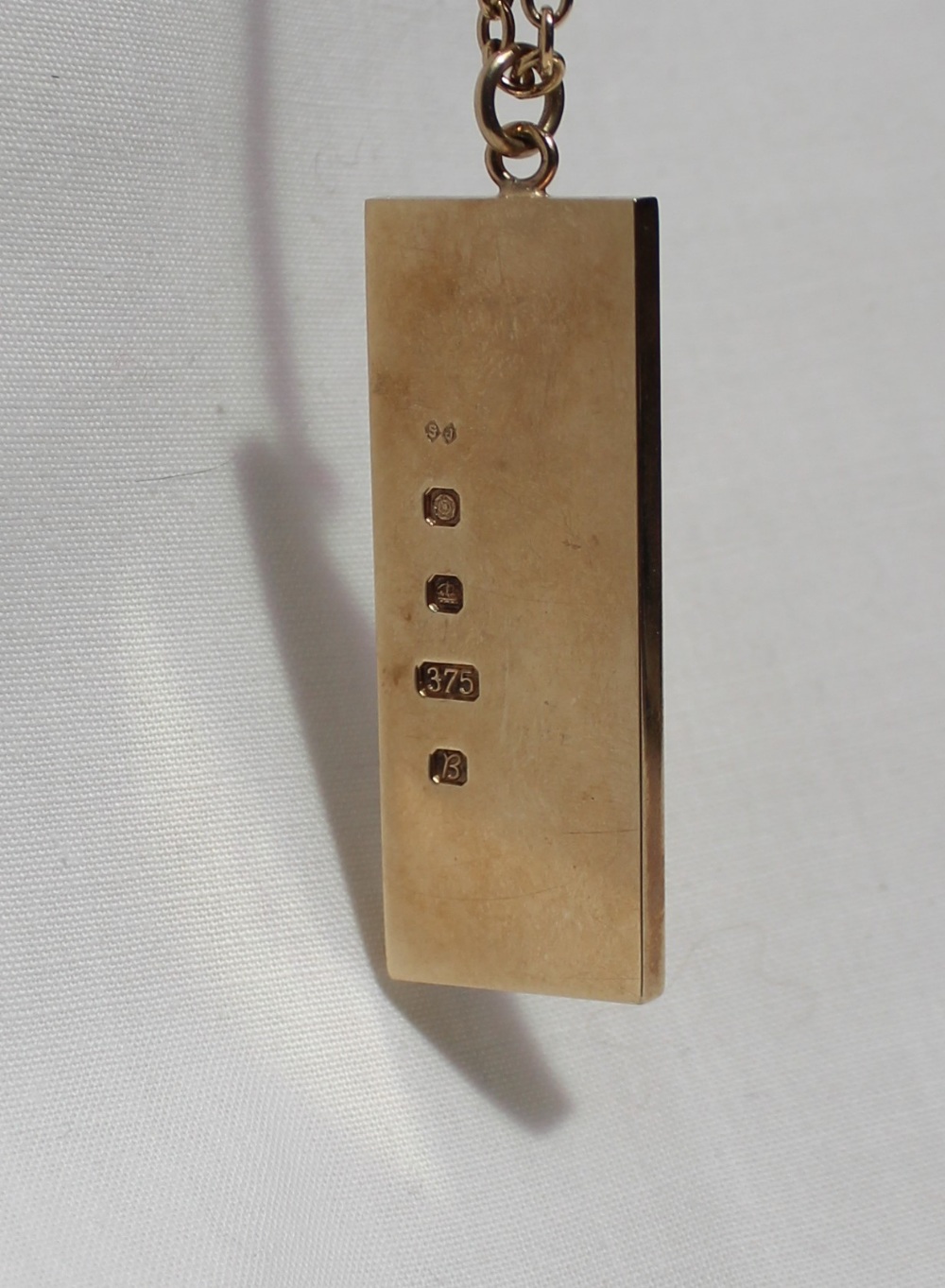 A 9ct yellow gold ingot, decorated with a lion, on a yellow metal chain marked 9ct, - Image 2 of 3