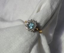 An aquamarine and diamond cluster ring, the step cut aquamarine with cut corners, claw set,