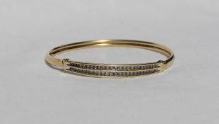 A yellow metal diamond set bangle with fifty diamonds set side by side, marked 14K,