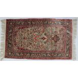 A red silk rug, with scrolling floral and leaf decoration with birds and vase of flowers,