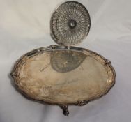 A George V silver salver, with a shaped and floral border, signed to the plate, on three feet,