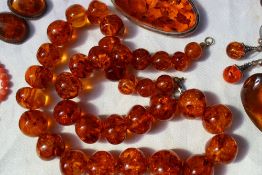 A modern amber bead necklace together with a similar brooch, three pairs of earrings,