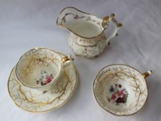 A 19th century English porcelain trio decorated with a spray of garden flowers and gilt roots,