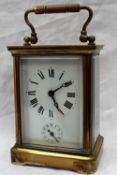 A brass carriage clock, the enamel dial with Roman numerals and an alarm dial,