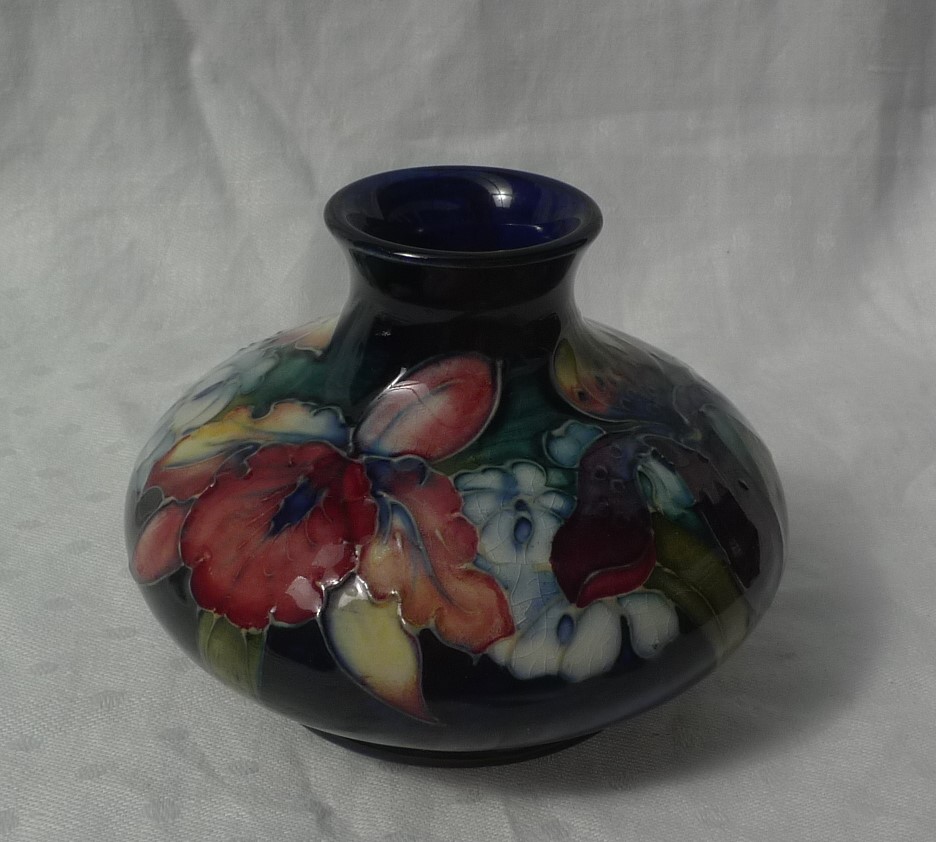 A Moorcroft vase of squat baluster form, decorated with orchids to a blue and green ground,