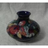 A Moorcroft vase of squat baluster form, decorated with orchids to a blue and green ground,