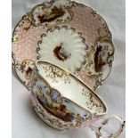 A 19th century English porcelain tea cup and saucer, painted with vignettes of cottages,