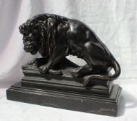 A cast iron model of a lion on a kill, standing on a rectangular plinth, 29.