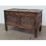 An 18th century oak coffer the rectangular panelled top above a carved two panelled front on stiles,