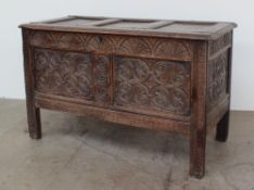 An 18th century oak coffer the rectangular panelled top above a carved two panelled front on stiles,