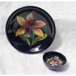 A Moorcroft plate decorated with a lily type flower to a green and blue ground, 18.