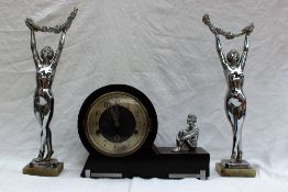 An Art Deco clock garniture, comprising an ebonised mantle clock with chrome seated figure,