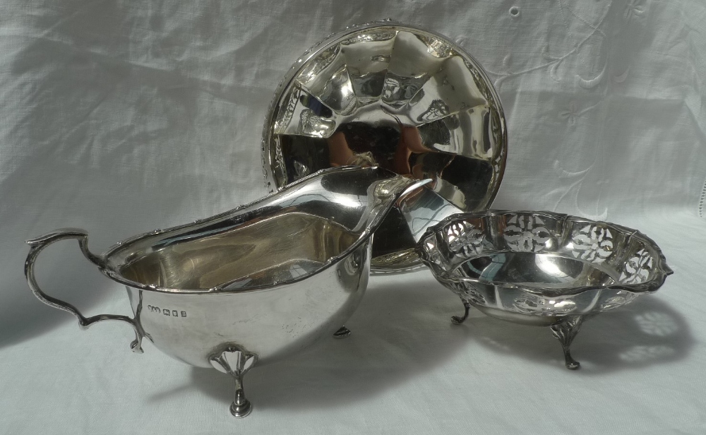 A George V silver sauce boat with a flower head and line rim on three shell capped legs and pad