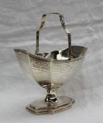 A late George III silver swing handled sugar basket, of oval panelled form on a spreading foot,