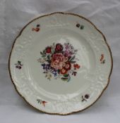 A Nantgarw porcelain plate with a scalloped edge and moulded border painted with single flowers,