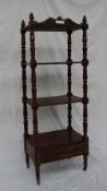 A Victorian rosewood whatnot with turned finials above four shelves and a drawer supported by lotus