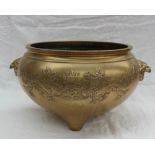 An oriental gilt bronze bowl decorated with dragons chasing a pearl with mask handles on three feet,