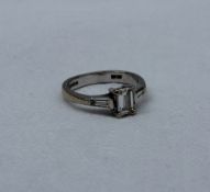 A solitaire diamond ring, the emerald cut diamond measuring 5mm x 4mm x 2mm,