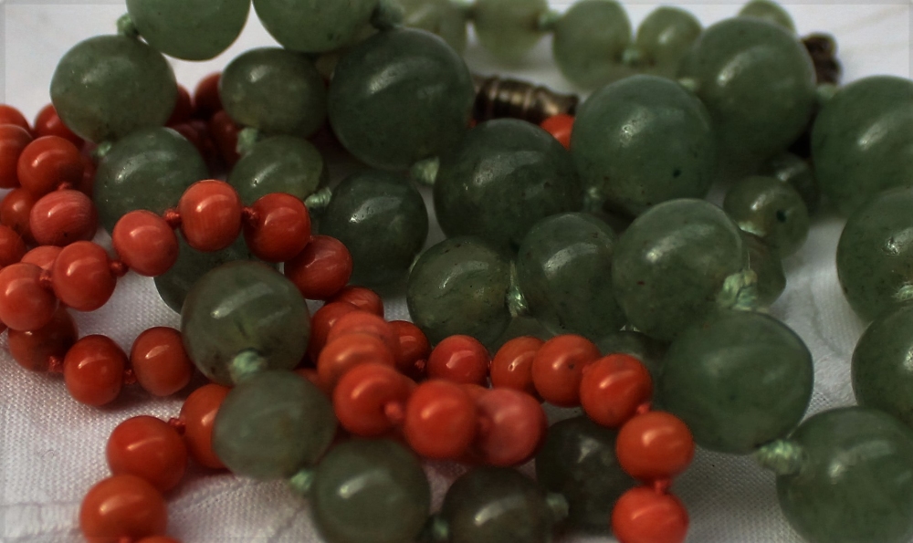 A green jade bead necklace, on a knotted cotton thread with a twist clasp,