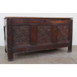 An 18th century oak coffer the planked rectangular top above a three panelled front carved with