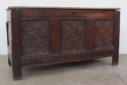 An 18th century oak coffer the planked rectangular top above a three panelled front carved with