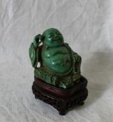 A Chinese hardstone figure of a seated happy Buddha with a ball in his right hand and a necklace in